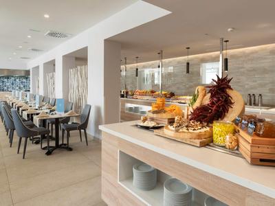 Modernes, helles Restaurant mit Buffetbereich und gedeckten Tischen in einem Hotel.