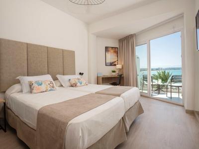 Schlafzimmer mit zwei Betten, großem Fenster und Blick auf Terrasse und Meer