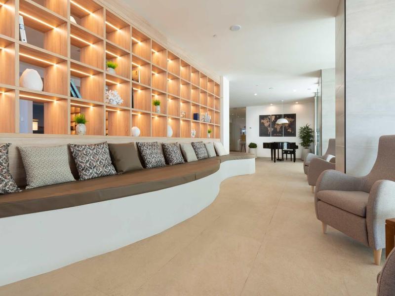 Modern hotel lounge with curved bench seating, cushions, and decorative wall shelves.