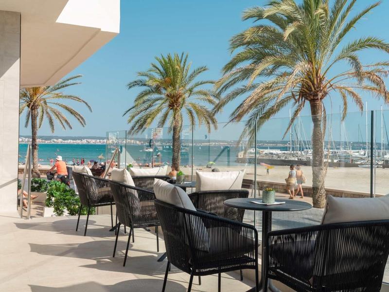 Cafe terrace with tables and chairs on the beach under palm trees