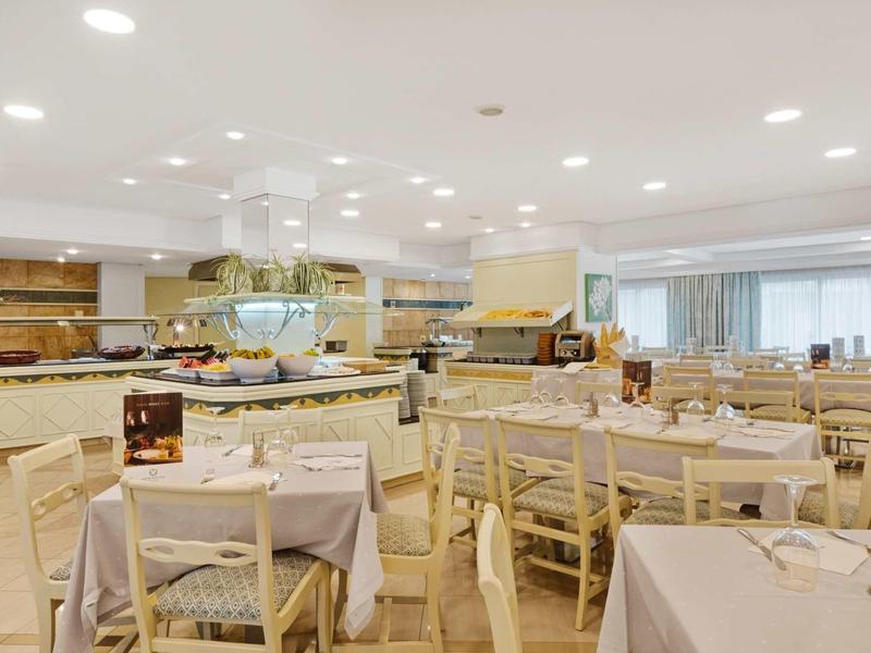 Salle à manger lumineuse et moderne avec tables dressées et chaises en bois dans un hôtel.