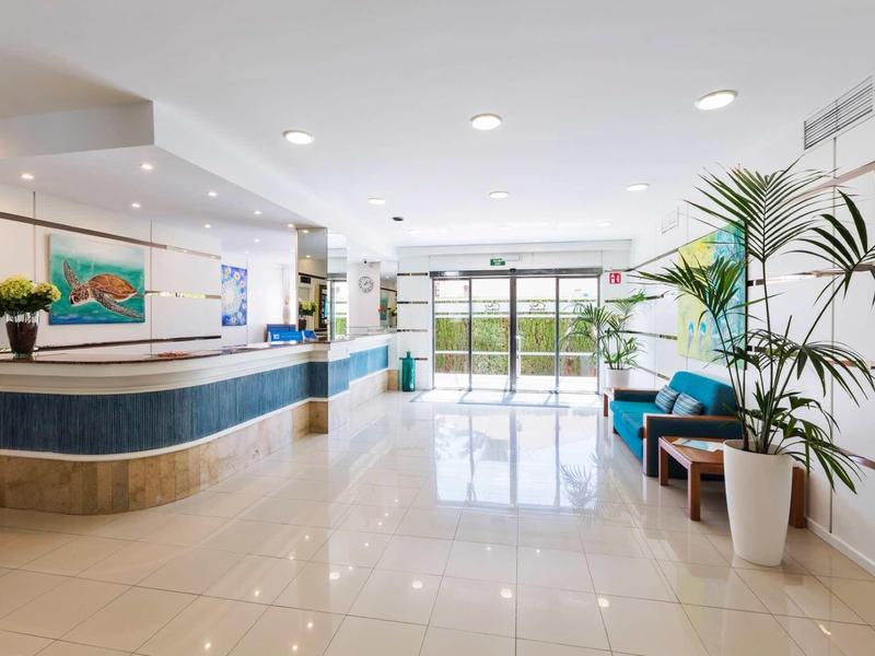 Heller, moderner Empfangsbereich mit blauer Theke, Pflanzen und großem Panoramafenster.