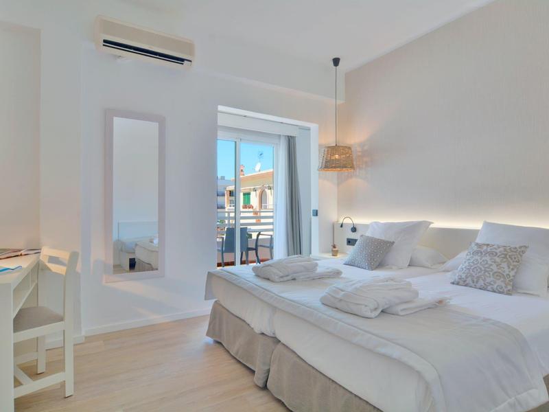 Chambre d'hôtel lumineuse et moderne avec lit double, balcon et décoration minimaliste.