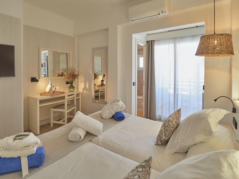 Chambre d'hôtel lumineuse avec deux lits simples et balcon avec vue sur la mer.