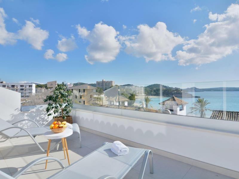 Terrasse avec chaises longues et vue sur la mer sous un ciel ensoleillé.