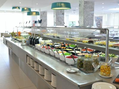 Buffet con insalate e bevande in una sala da pranzo moderna e luminosa di un hotel.