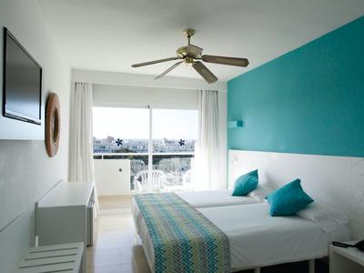 Modernes Hotelzimmer mit zwei Einzelbetten, türkisfarbenen Akzenten und Balkon mit Blick auf die Stadt