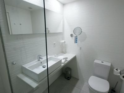 Modernes, minimalistisches Badezimmer mit Waschbecken, Toilette und Haartrockner an der Wand.