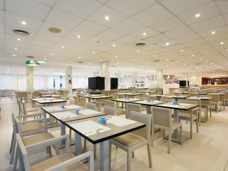 Sala da pranzo luminosa e moderna con molti tavoli e sedie disposti in file