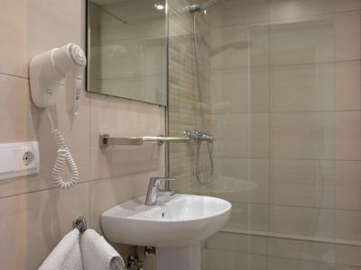 Modernes Badezimmer mit weißem Waschbecken, Dusche und Wandföhn