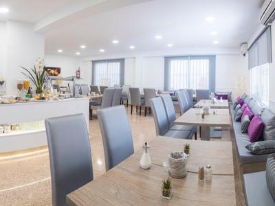 Café moderno y luminoso con largas mesas de madera, sillas grises y grandes ventanas