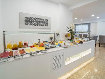 Buffet avec divers jus, charcuteries et plats de petit-déjeuner dans une salle à manger d'hôtel moderne