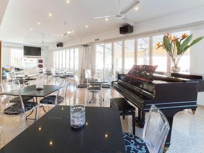 Salle à manger lumineuse avec un piano à queue, mobilier moderne et grandes fenêtres avec vue.