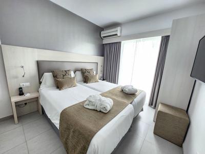 Habitación de hotel moderna con cama doble, aire acondicionado y balcón.