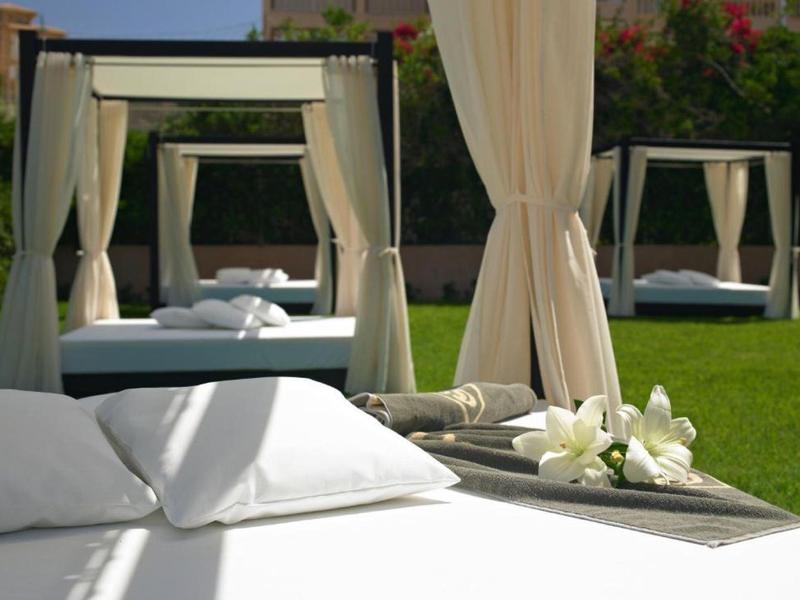 Drei weiße Pavillons mit Vorhängen auf grünem Rasen, Nahaufnahme von Kissen und Blumen auf einem Tablett.