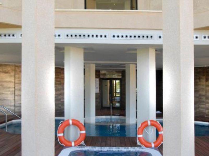 Innenpool mit Säulen, zwei orangefarbenen Rettungsringen und hellem Marmorboden in modernem Raum.