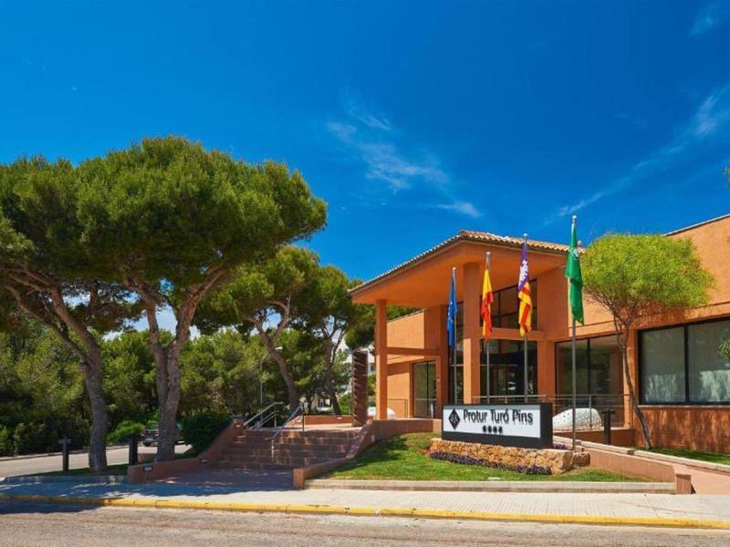 Gebäude mit roten Wänden, umliegenden Bäumen und einer Einfahrt, darunter Straßenschild "City Hall".