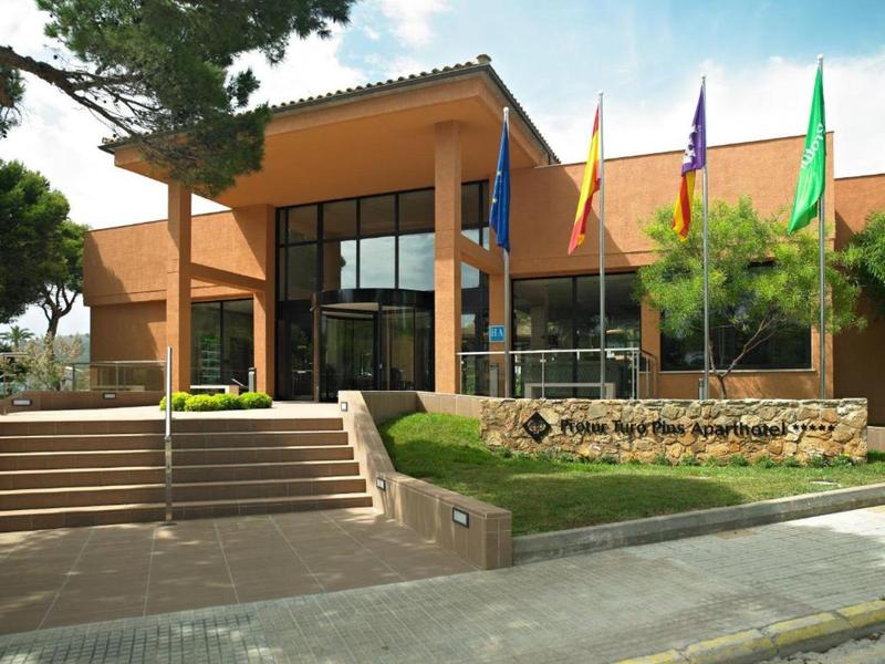 Modernes Verwaltungsgebäude mit großen Glasfronten, roten Ziegeln und mehreren Flaggen davor.