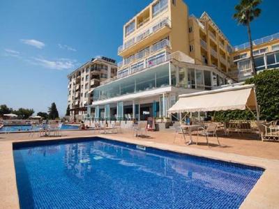 Hôtel avec grande piscine extérieure et terrasse sous un ciel bleu