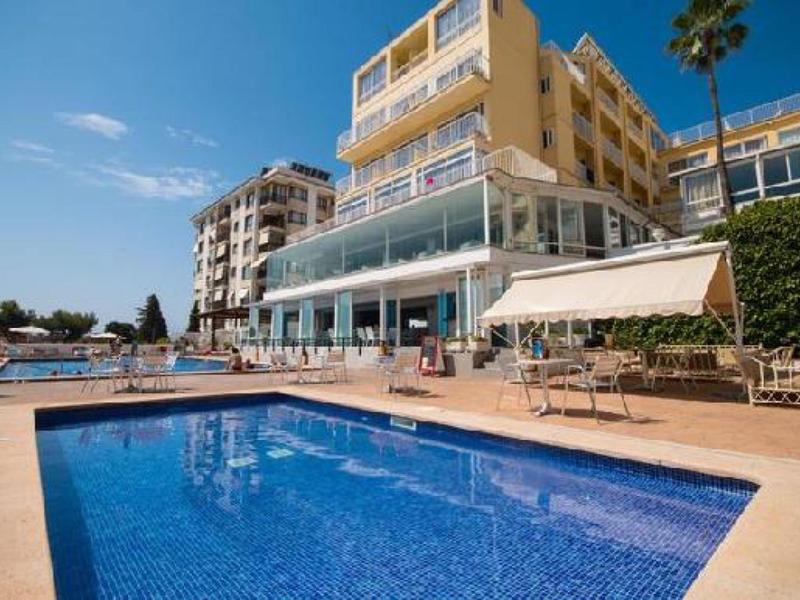 Hotel s velkým venkovním bazénem a sluneční terasou pod modrou oblohou