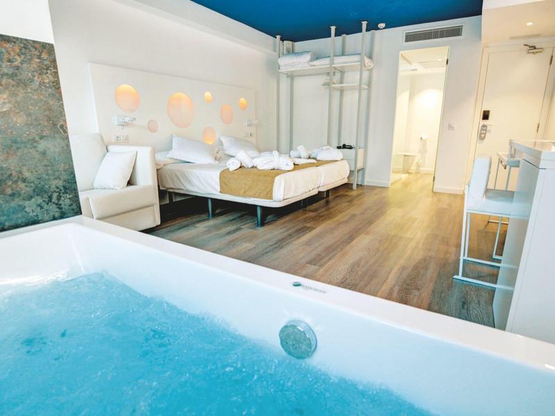 Modern hotelkamer met tweepersoonsbed en binnen whirlpool op houten vloer.