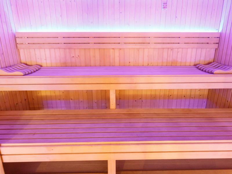 Houten saunabanken met twee handdoeken en paarse verlichting op de achtergrond