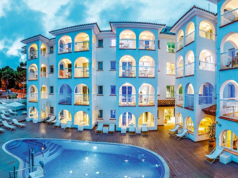 Modern hotelcomplex met verlicht zwembad en meerlaagse gebouwen bij schemering