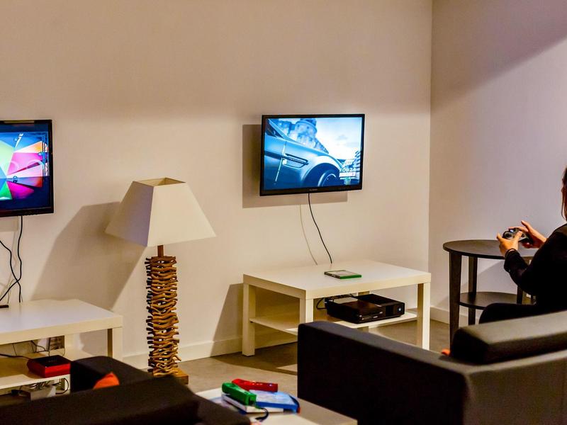 Persoon zit op bank in moderne woonkamer met tv en spelconsole