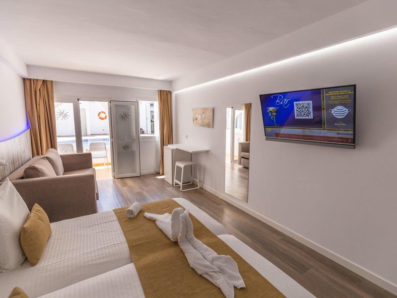 Moderne hotelkamer met twee bedden, bank, tv en toegang tot een balkon.