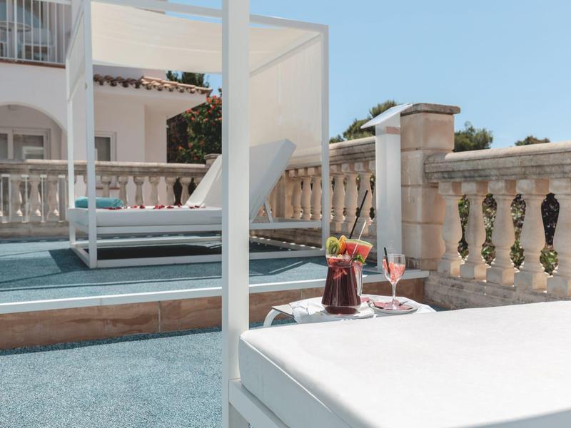 Terras met ligstoel, drankjes en uitzicht op mediterraan gebouw bij heldere lucht