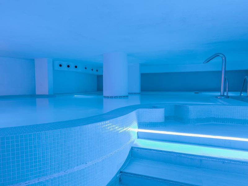 Moderne binnenzwembad met blauwe verlichting en trappen in een hotel.