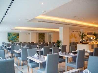 Restaurant d'hôtel lumineux et moderne avec des chaises grises et des tables dressées.