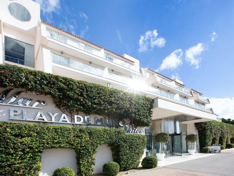 Nowoczesny hotel z białą elewacją i zielonymi ścianami pod bezchmurnym niebem.