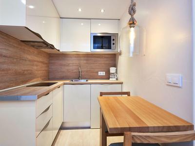 Kleine moderne kitchenette met houten aanrechtblad en geïntegreerde eethoek.