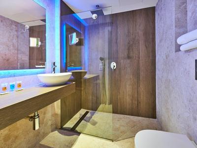 Moderne badkamer met inloopdouche, wastafel en handdoeken aan de muur.