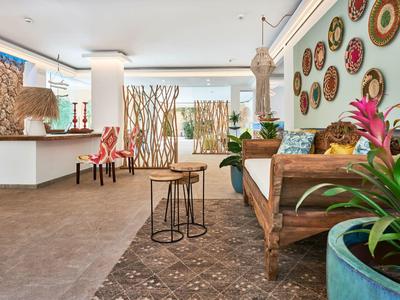 Moderne hotel lobby met zithoek, wanddecoraties en planten in grote potten.