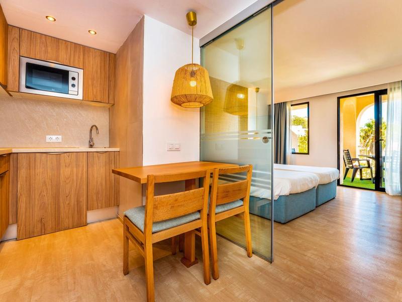 Camera d'hotel accogliente con angolo cottura, zona pranzo, letto matrimoniale e accesso al balcone.