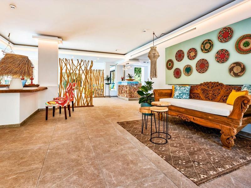 Luminosa hall dell'hotel con area salotto e decorazioni murali con cestini dai toni caldi.