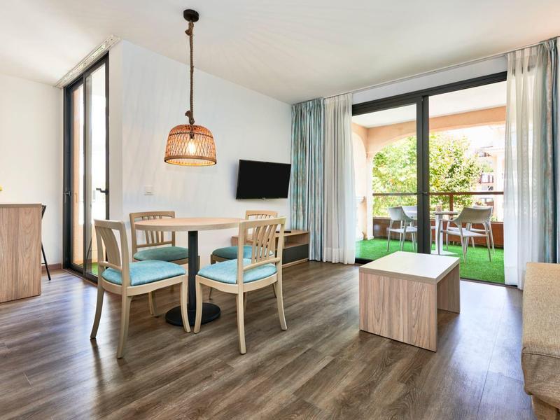 Lichte, moderne woonkamer met eettafel, stoelen en toegang tot een terras met planten.