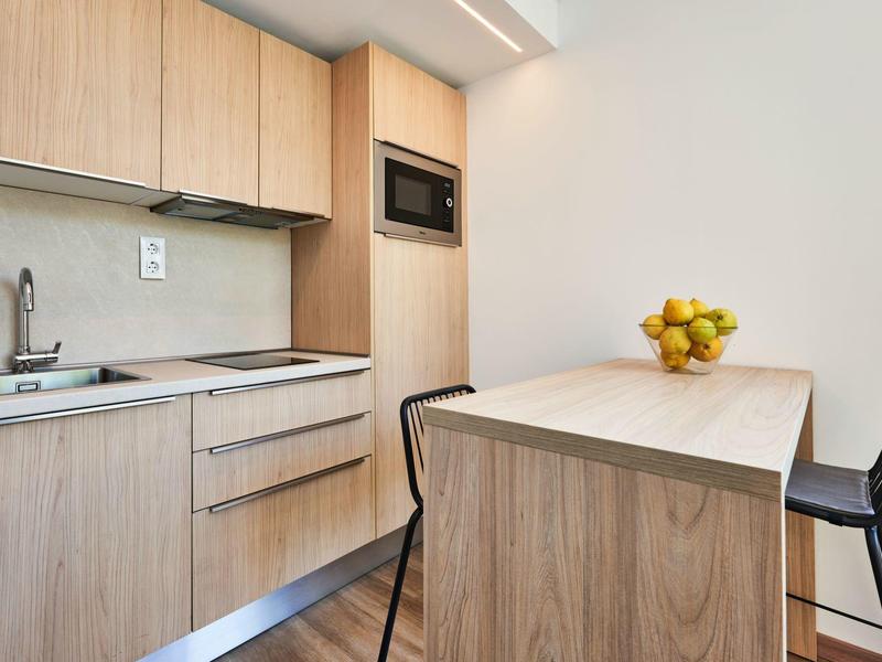 Moderne keuken met houten fronten en een bartafel met twee zwarte krukken.