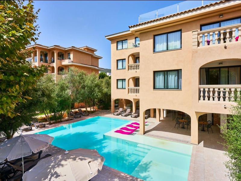 Hotelgebouw met balkons en zwembad omgeven door bomen en parasols