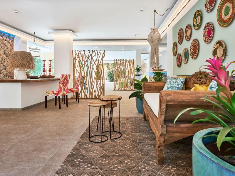 Moderne hotel lobby met zithoek, wanddecoraties en planten in grote potten.