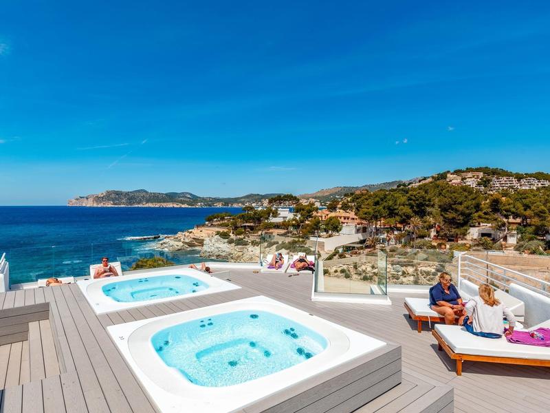 Terasa s vířivkou a výhledem na moře, venkovní lázně pod modrou oblohou.