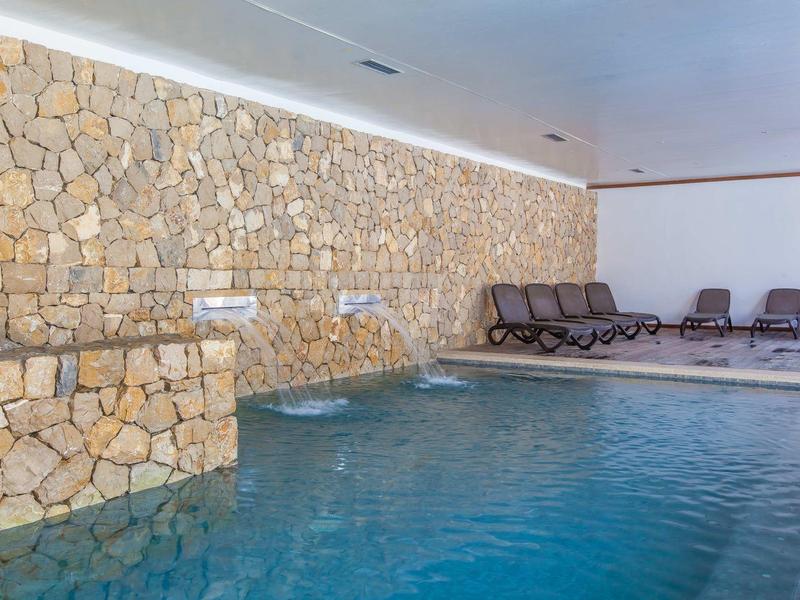 Vnitřní bazén s kamennou zdí a lehátky podél okraje.
