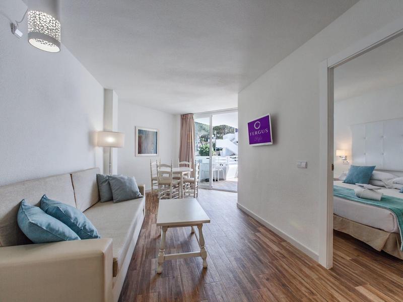 Moderní obývací pokoj s pohovkou, konferenčním stolkem, jídelnou a sousední ložnicí s manželskou postelí.