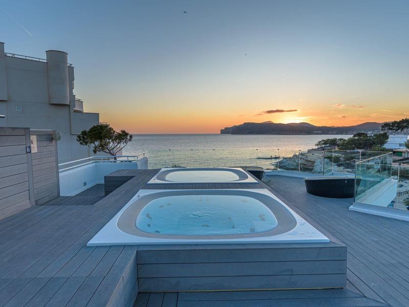 Venkovní vířivka na terase s výhledem na moře při západu slunce.