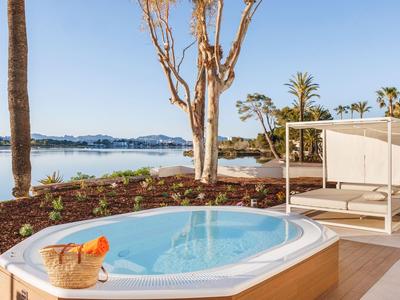 Whirlpool auf einer Terrasse mit Blick auf das Meer und umgeben von Palmen und Pflanzen.