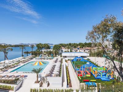Complexe hôtelier avec piscine, parasols et aire de jeux au bord de la mer.
