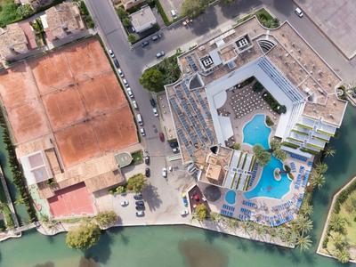 Luftaufnahme von Tennisplätzen und einem angrenzenden Schwimmbad mit architektonisch gestaltetem Bereich.