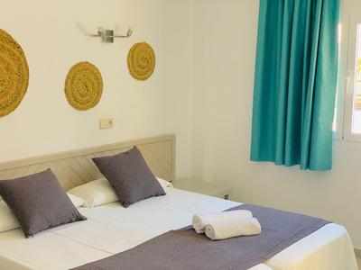 Lichte hotelkamer met een groot bed, turquoise gordijnen, drie ronde wanddecoraties en opgevouwen handdoeken.